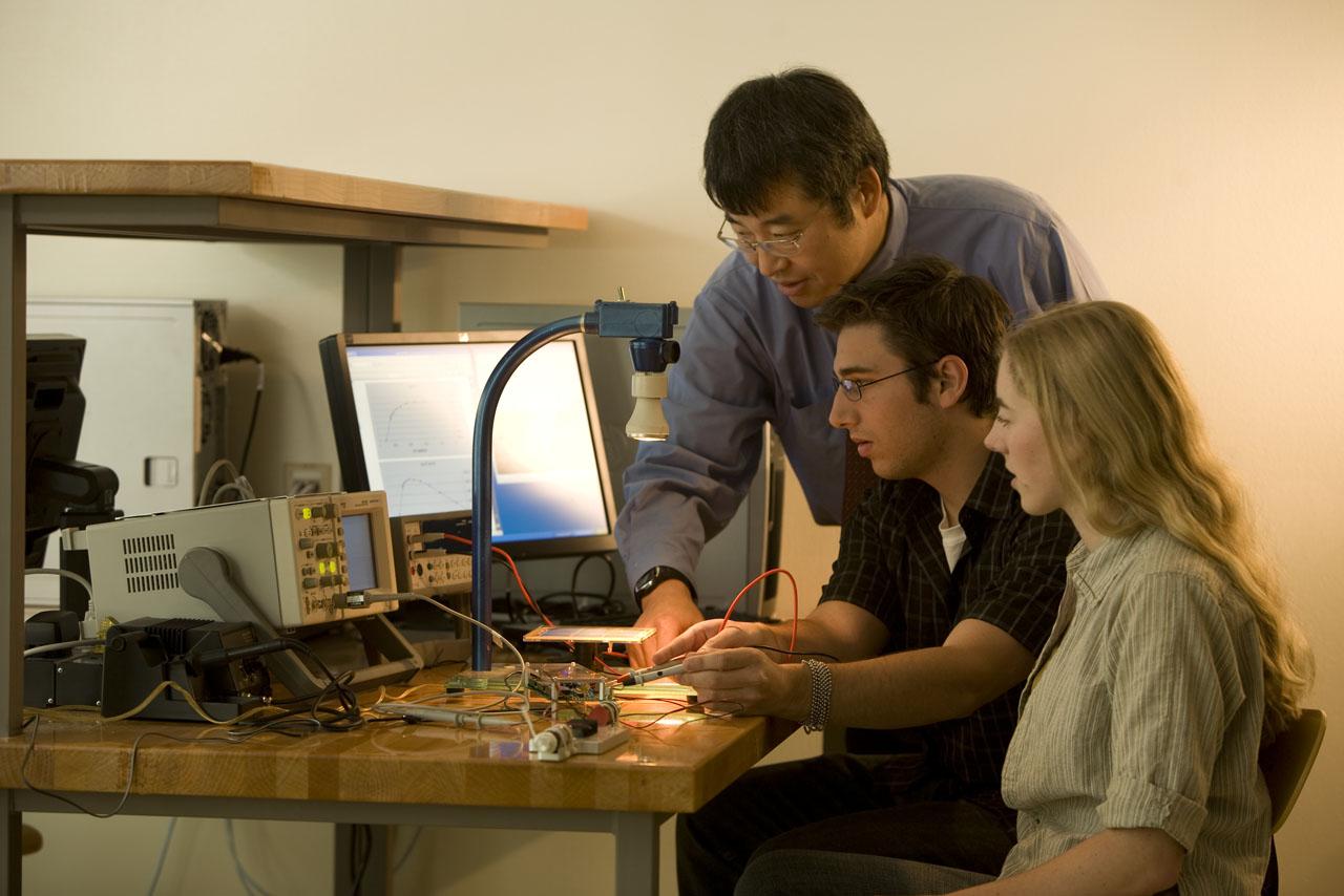 A professor is helping two students with their 电 engineering project.